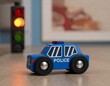 © Esta Webster - petite voiture de police bleu en bois dans un décor de maison avec un feu tricolor en ia