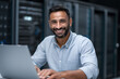 © UniqGraphicX - Indian IT engineer working on laptop in server room for system maintenance