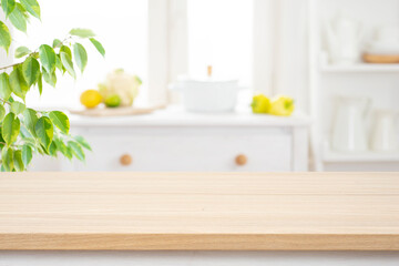 Wall Mural - beige wooden table for product presentation over blur kitchen interior background and green plant le