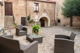 A view of an old, ancient palace's inner court, showcasing traditional stone architecture, a cobblestone floor, and historic details. The light and shadows highlight the building's age and grandeur.
