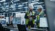 © Gorodenkoff - Factory Office: Hispanic Male Manager Using Tablet And Talking To Caucasian Female Engineer At Autonomous Manufacturing Plant. Colleagues Working On Sustainable Energy Engines Production.
