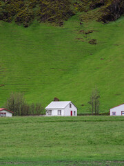 Wall Mural - A white house surrounded by mountain and green field.