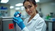 © Leonardo - Una técnica con guantes azules coloca el vial de muestra de sangre en la nevera portátil. Etiqueta roja de riesgo biológico en la superficie, suelo de baldosas grises del laboratorio