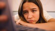 © Monkey Business - Depressed Teenage Girl Lying On Bed At Home Looking At Mobile Phone