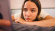 © Monkey Business - Depressed Teenage Girl Lying On Bed At Home Looking At Mobile Phone