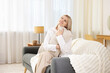 © New Africa - Dreams come true. Woman with pillow thinking about something on sofa at home