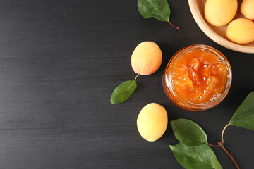Wall Mural - tasty apricot jam and fresh fruits on black wooden table, flat lay. space for text