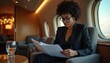 © Pete - Focused African American woman in black suit reads documents indoors. Professional executive wearing glasses concentrating on papers, planning strategy. Businesswoman enjoys productive work session