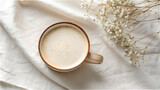 Overhead view of a creamy latte in a rustic mug with dried flowers