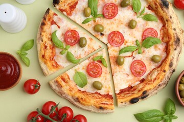 Wall Mural - delicious cut pizza and ingredients on light green background, flat lay