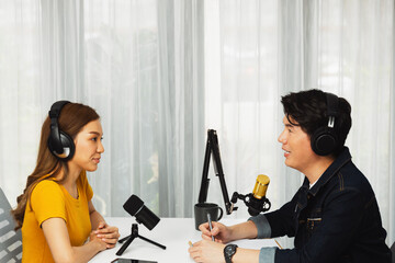 Smiling radio influencer host wearing headphone interviewing woman speaker sharing information to listeners on social media online website live streaming channel at morning at studio record. Infobahn.