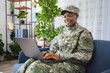 © Jelena - Smiling Female Soldier Working on Laptop at Home