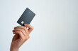 © SVITLANA - Close-up of a hand holding a modern black credit card with a chip, isolated on a clean white background. Ideal for finance, banking, or shopping concepts.