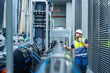© CandyRetriever  - Industrial engineering technician worker working maintenance building exterior plumbing systems. Male engineer in safety uniform speaking on radio and checking pipeline valves at construction site.