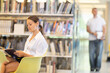 © JackF - Female student is attentively reading a book and sitting in the lecture hall against the background of shelves with books.