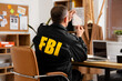 © Pixel-Shot - Mature FBI agent with evidence at table in office, back view