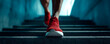 © sornram - A close-up view of a person wearing red running shoes while ascending a staircase, symbolizing motivation and fitness in an urban environment.