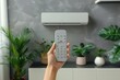 © Ummeya - Hand holding remote control near air conditioner indoors