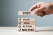 © Kazi - Hand placing wooden block with 2026 on stack of blocks with plan goal action new year checklist concept