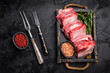 © Mironov - Raw Veal Short Rib, fresh beef meat with bone and herbs for cooking . black background. top view
