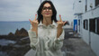 © Krakenimages.com - Woman wearing white shirt and eyeglasses raising middle fingers at camera in front of white building; defiance.