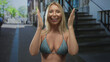 © Krakenimages.com - Woman wearing a blue bikini top with clasped hands praying in urban street scene near building staircase; hope.