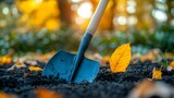 Gardener uses shovel to dig soil in autumn landscape filled with fallen leaves