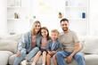© New Africa - Happy family sitting on sofa at home