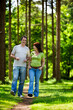 © track5 - A happy mature couple strolling through a leafy forest path smiling and enjoying a sunny summer's day outdoors. From a series of images.