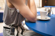 © RooM The Agency - Close-up of a woman with type 1 diabetes wearing a continuous glucose blood monitor sitting at a cafe with a hot drink