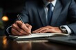 © jaya - Businessman writing in a notebook
