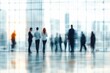 © dgete - Blurry silhouettes of people walking and standing inside a modern glass building with city skyline visible outside, evoking a sense of motion and urban life