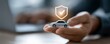 © Rifqi - Executive's hands holding a miniature silver car with shield graphic overlay with check mark. Concept for auto insurance comparison, financial vehicle safety and transportation protection