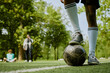 © Seventyfour - Teenage boy standing on soccer field placing foot on ball while two other teenagers sitting and standing in background on grass outdoors