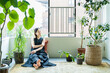© TAGSTOCK2 - 観葉植物に囲まれてリラックスする女性
