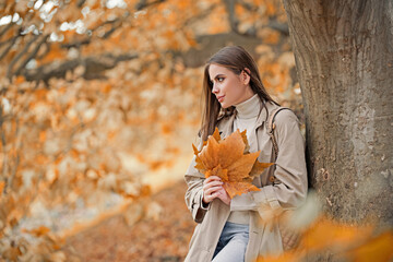 Wall Mural - Autumn woman portrait in autumn fall. Woman with fall leaves. Romantic portrait in autumn foliage. Model on autumn nature. Woman with falling leaves.