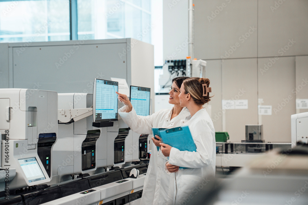 Scientists analyzing data on monitors in modern medical laboratory ...