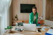 © BusinessClass by W61 - Happy young fashion designer holding fabric samples and working on laptop at desk