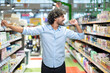 © Liubomir - A cheerful man showing excitement while dancing in a supermarket with brightly lit aisles.