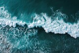 Aerial view of crashing waves. Dark teal ocean water with frothy white crests of waves breaking