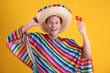 © New Africa - Happy man in sombrero hat, colorful poncho and maracas on yellow background