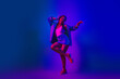 © deagreez - Stylish young woman dancing in vibrant neon lights, wearing denim and expressing happiness and energy