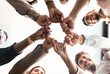 © Prostock-studio - Teamwork, Power And Partnership Concept. Below view of multucultural group of smiling people making fist bump standing in circle. Workers doing fist pump together celebrating good deal