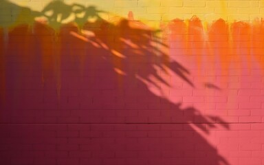Wall Mural - Photo of shadow of plant leaves on a brick wall with a gradient of yellow, orange, and pink colors