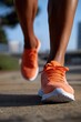 © Iryna - Close-up of athletic african adult running in orange sneakers on urban path