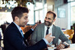 © Davor - Two businessmen discussing work over laptop in coffee shop