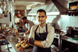 © Davor - Smiling young chef standing confidently in gourmet restaurant kitchen