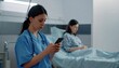 © scot - Nurse using a mobile phone in a hospital room.