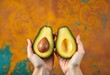 © Chaweewan - Smiling hands hold two avocado halves against a vibrant backdrop,   ripe,  closeup