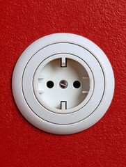 Wall Mural - of a recessed European socket on a red wall, with flat background and crisp white edges for visual contrast recessed European socket red wall background contrast white edge primary color clean 